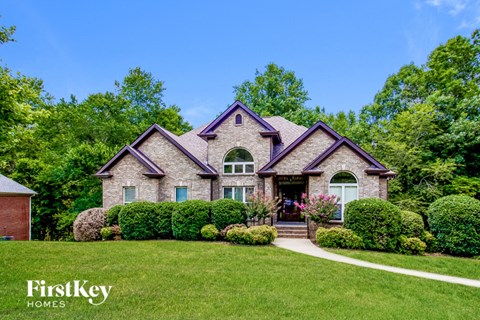 A house with a well-manicured lawn and a clear blue sky above.