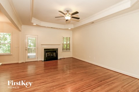 A spacious room with a fireplace and a ceiling fan.