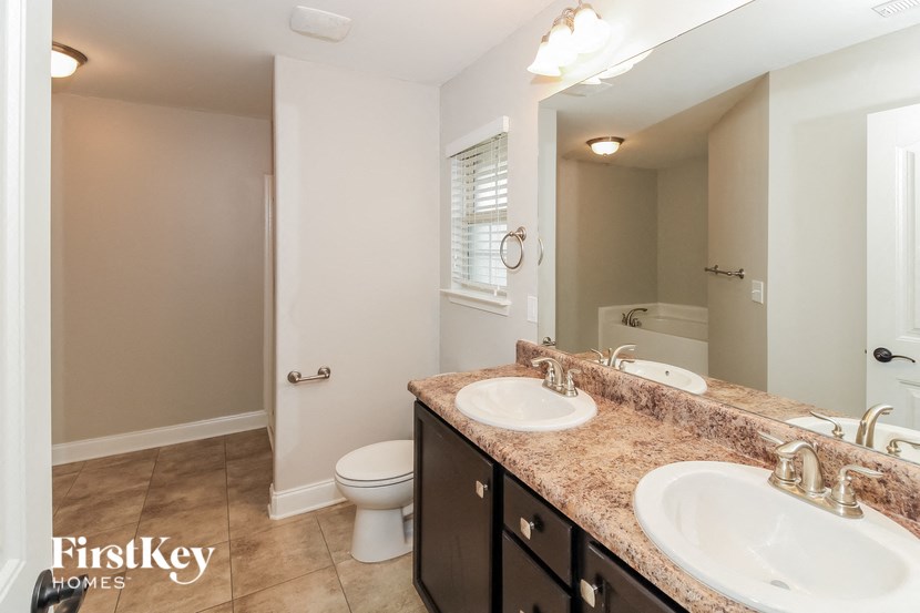a bathroom with two sinks and a toilet and a mirror