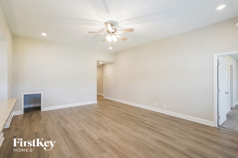 a living room with white walls and wood flooring and a ceiling fan