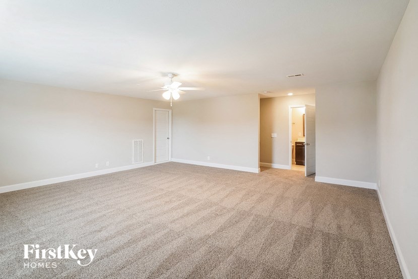 a spacious living room with carpeting and a ceiling fan