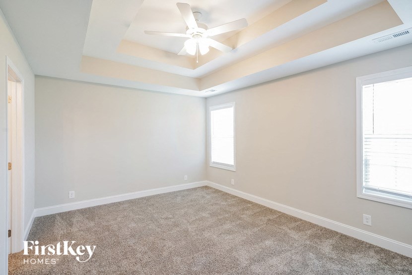 an empty room with a ceiling fan and two windows