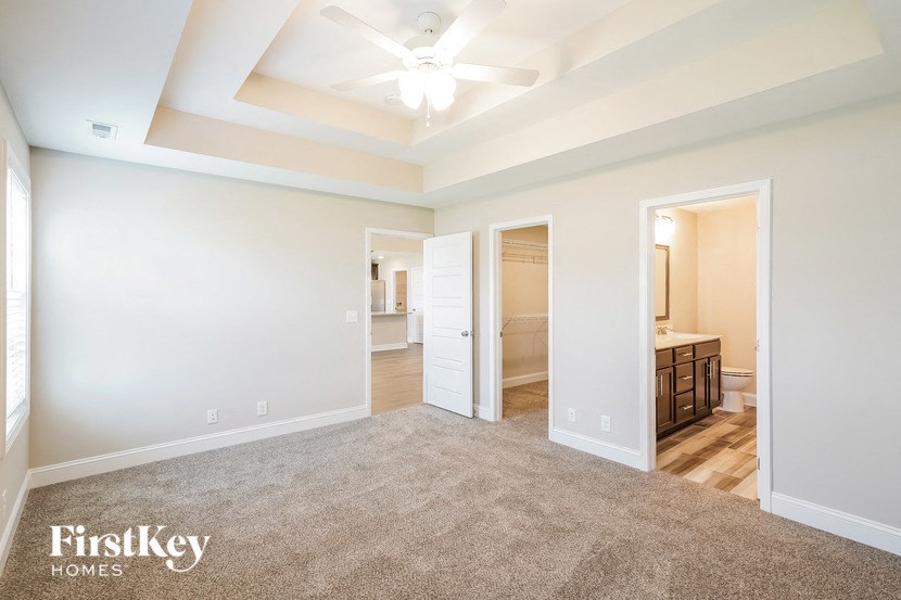 a spacious living room with carpet and a ceiling fan