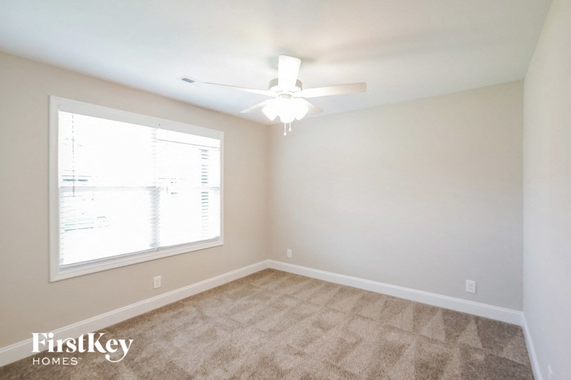 a bedroom with a large window and a ceiling fan