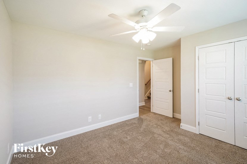 a bedroom with a ceiling fan and a door to a closet