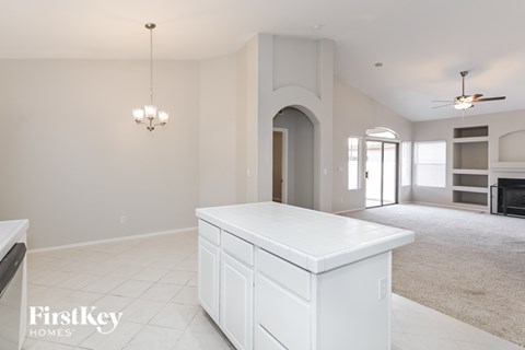 A spacious living room with a white kitchen island and a ceiling fan.