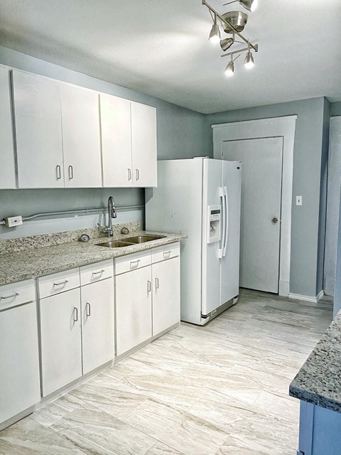 a white kitchen with white cabinets and a white refrigerator