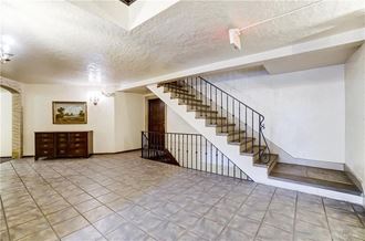 the lobby of a house with a staircase and a tiled floor