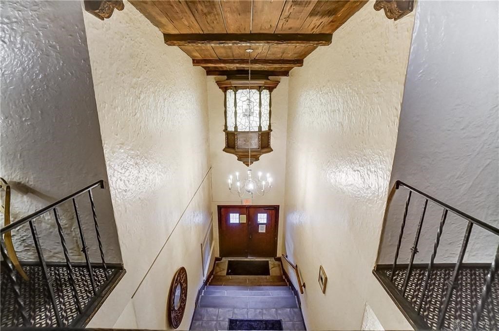 a hallway with stairs and a ceiling with a chandelier