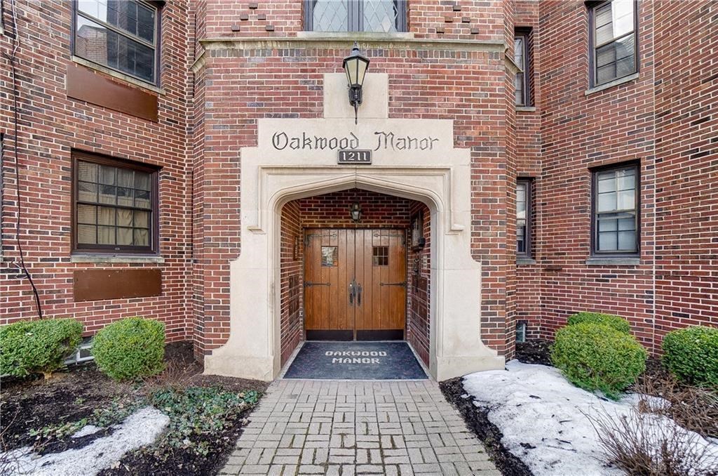 the front door of the oakwood manor apartment building in the snow