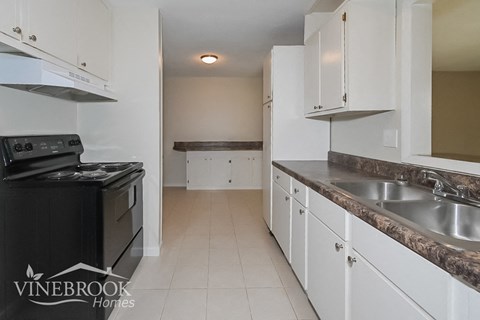 a kitchen with white cabinets and a stove and a sink