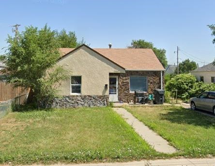 a brick house with a tree and a sidewalk