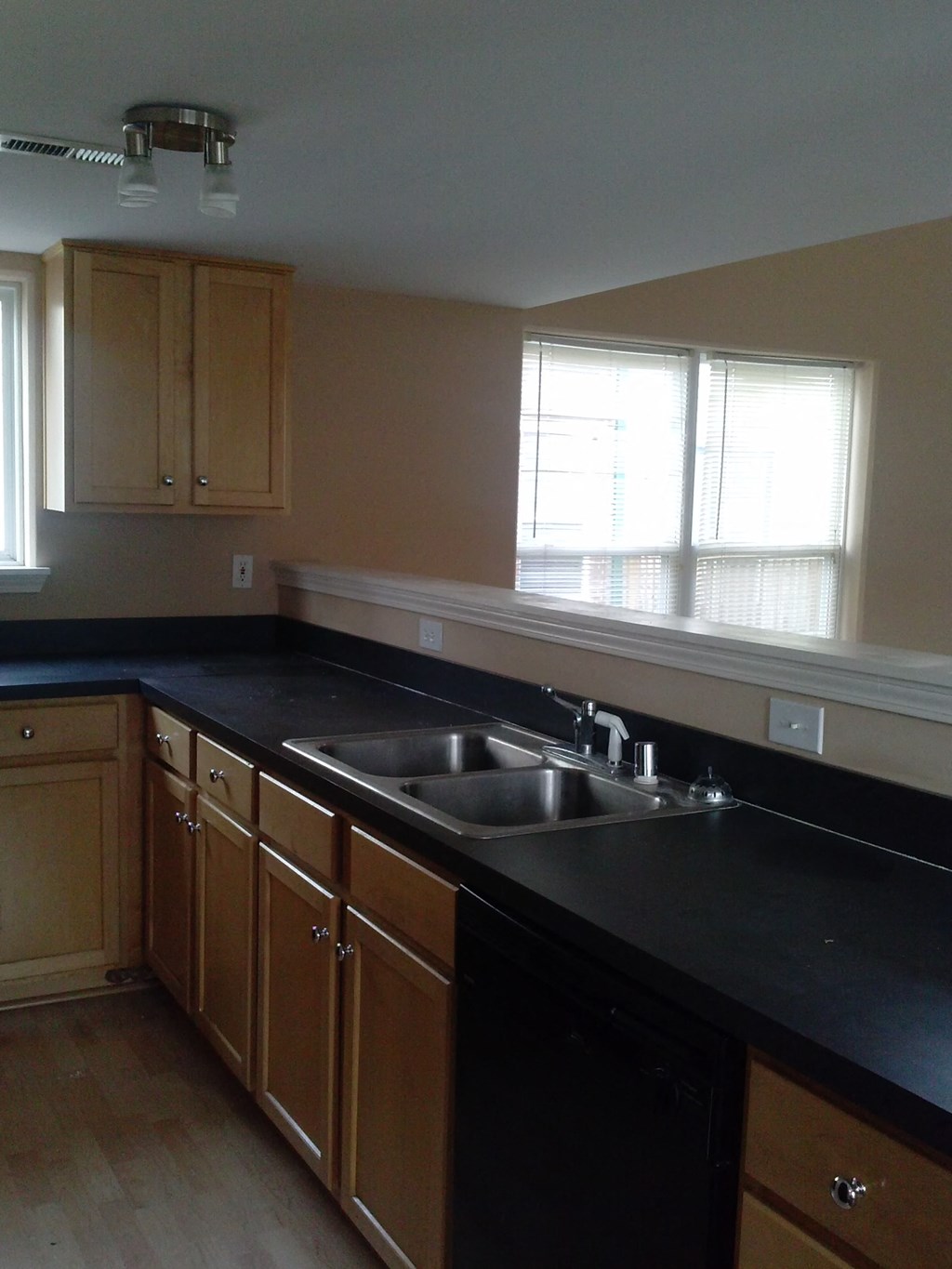 an empty kitchen with black counter tops and a sink