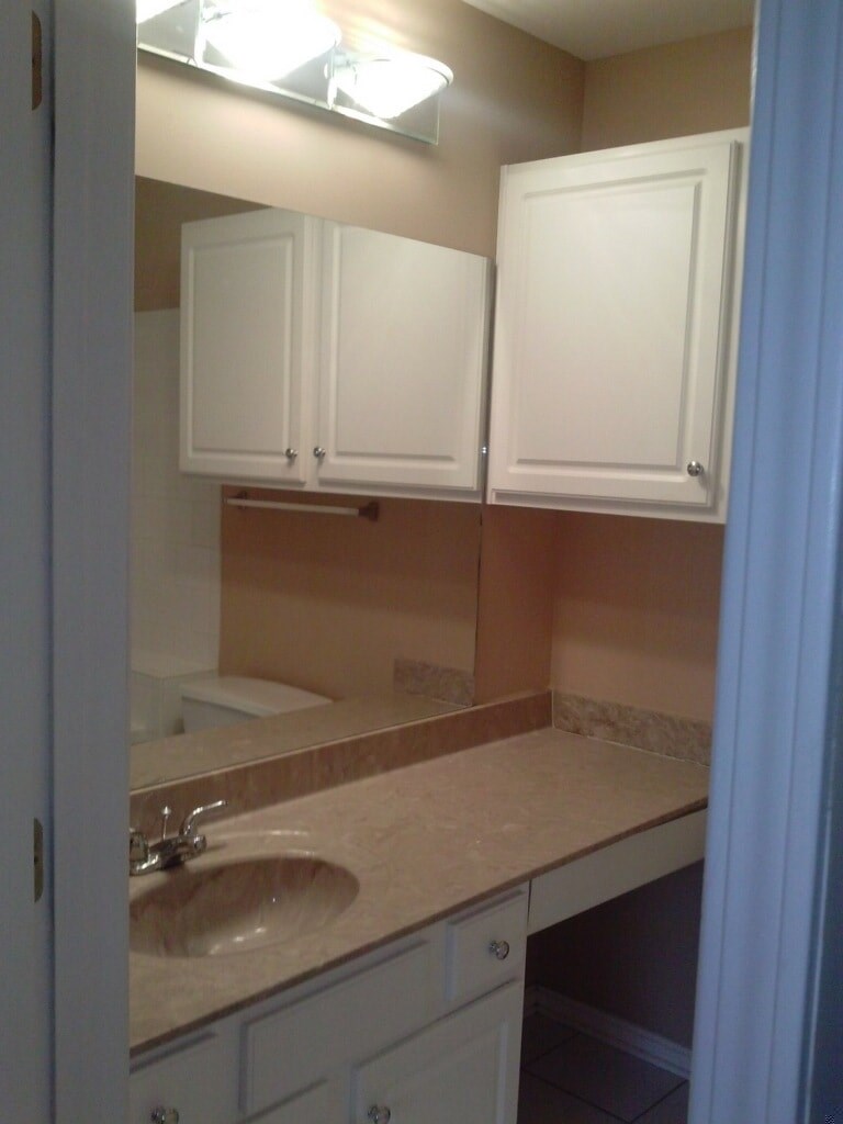 a bathroom with a sink and white cabinets