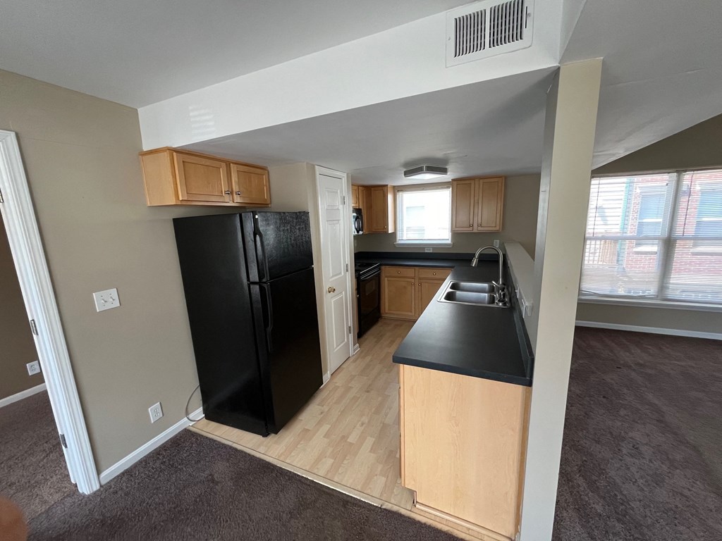 a kitchen with a black refrigerator and black counter tops