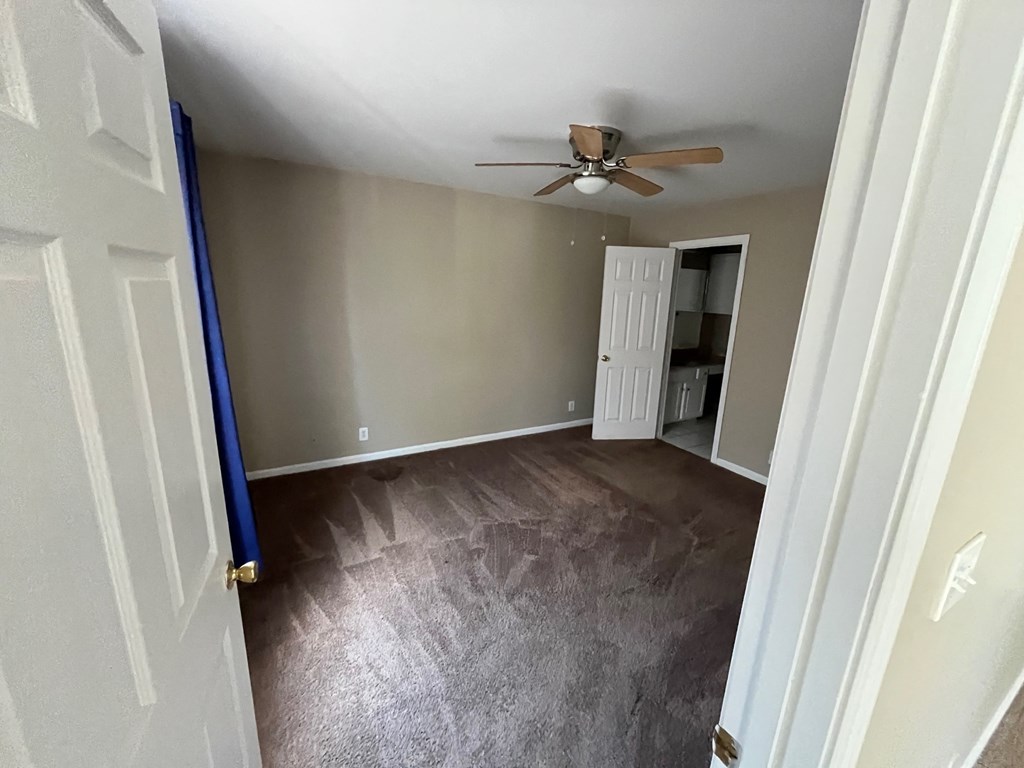 an empty living room with wood floors and a ceiling fan