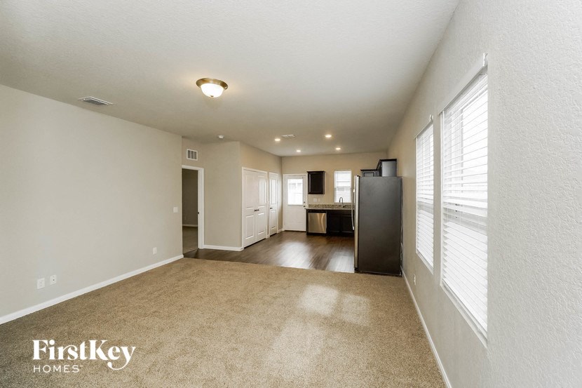 an empty living room and kitchen with a large window