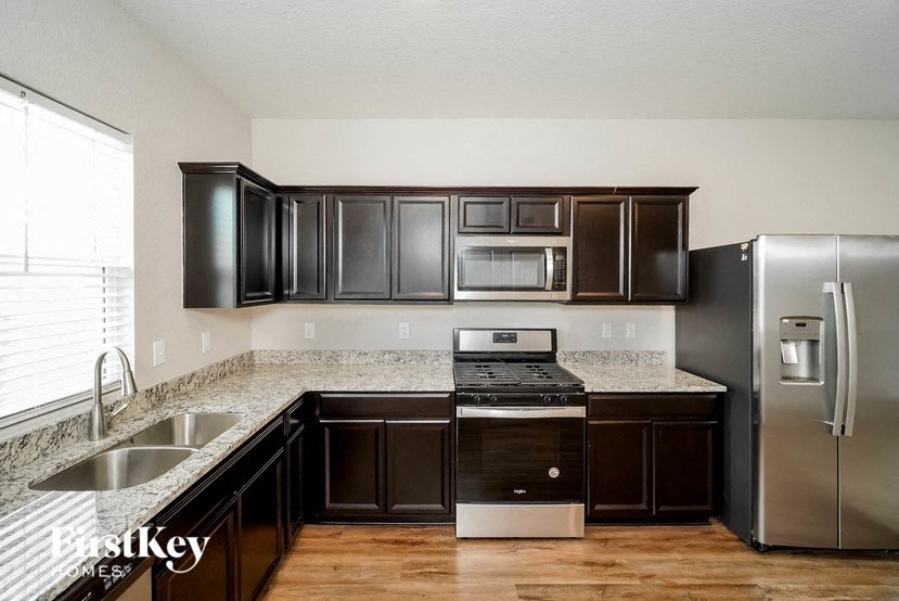 a kitchen with black cabinets and a stainless steel refrigerator