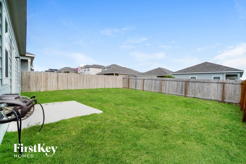 a backyard with a fence and a lawn and some houses