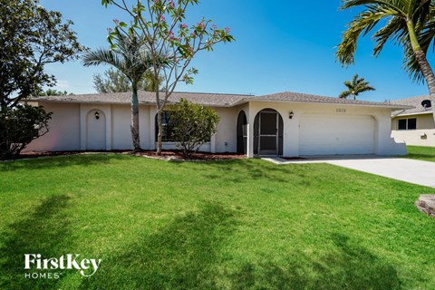 a white house with a lawn and palm trees