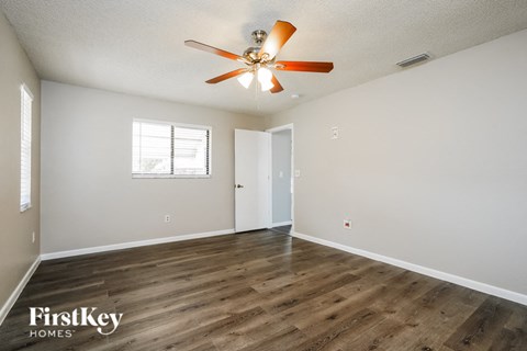a living room with white walls and a ceiling fan