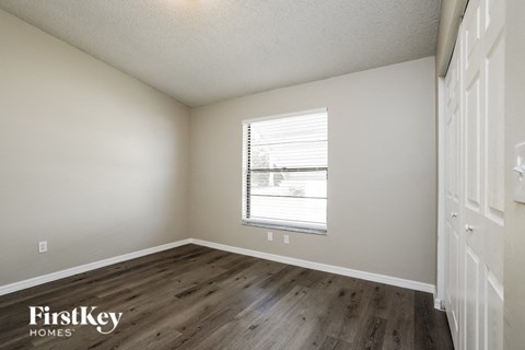a bedroom with a window and wooden floors