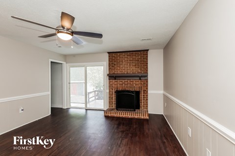 a living room with a brick fireplace and a ceiling fan