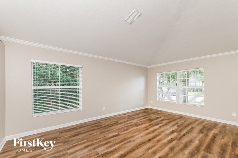 the living room of a home with wood flooring and two windows