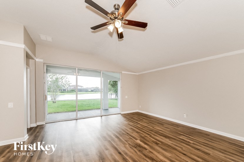 an empty living room with a ceiling fan and a sliding glass door