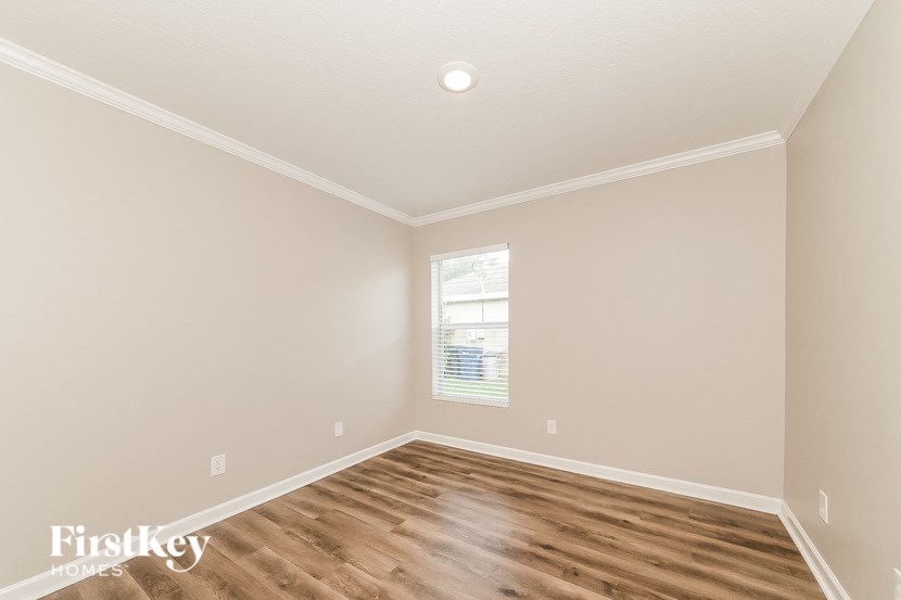 the second bedroom with hardwood flooring and a window