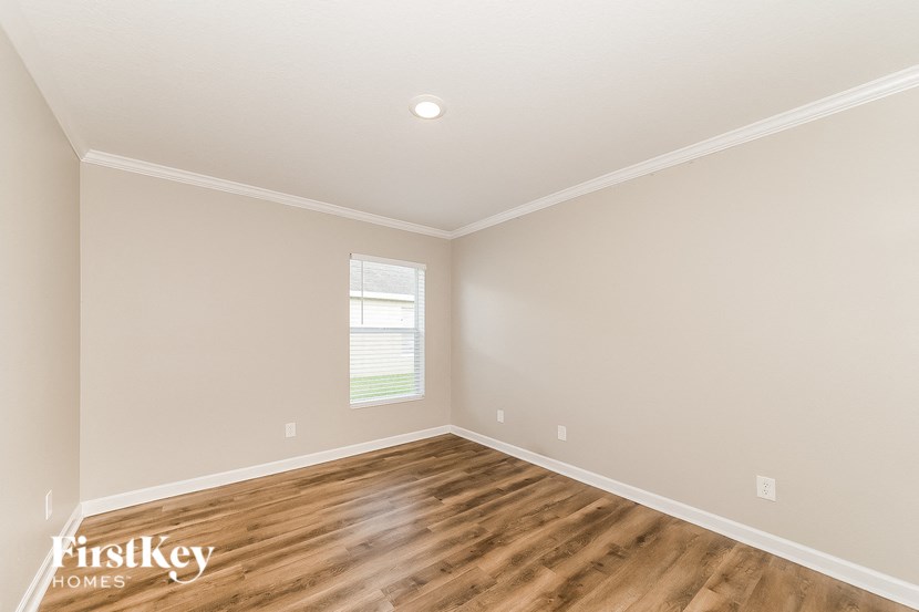 the second bedroom with hardwood flooring and a window