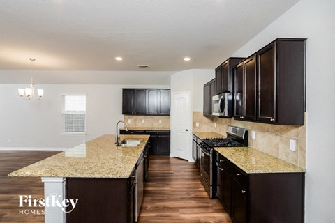 A kitchen with dark brown cabinets and a granite countertop.