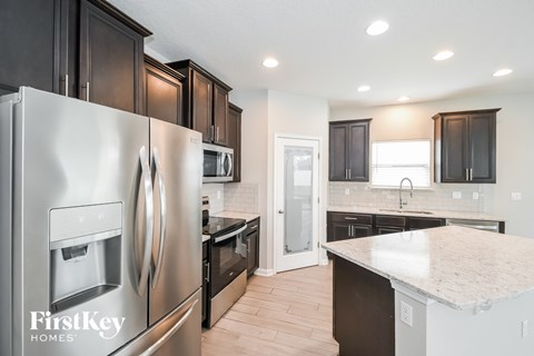 A kitchen with a stainless steel refrigerator and wooden cabinets.