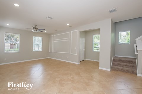 A spacious room with a fan and a staircase leading to another room.