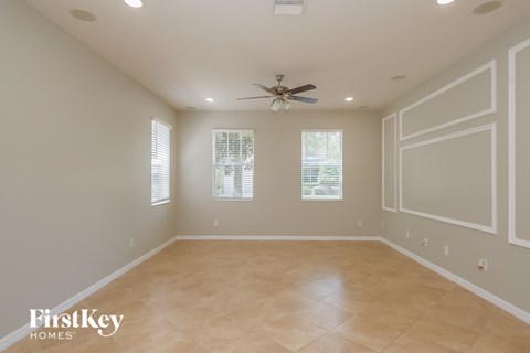A spacious room with a ceiling fan and two windows.