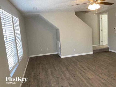 an empty living room with wood floors and a ceiling fan