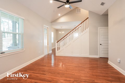 a living room with a staircase and a large window and a wood floor
