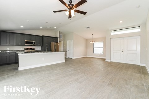an empty kitchen and living room with a ceiling fan