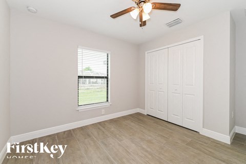 an empty bedroom with a ceiling fan and a window