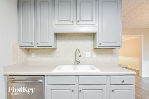 a white kitchen with white cabinets and a sink