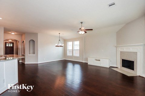 an empty living room with a fireplace and a ceiling fan