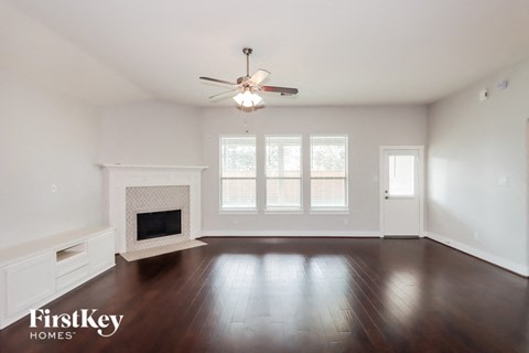 an empty living room with a ceiling fan and a fireplace