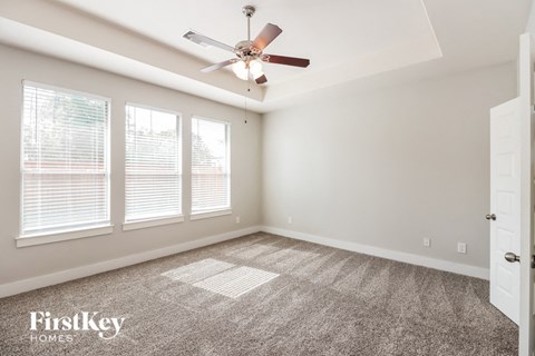 an empty room with a ceiling fan and three windows