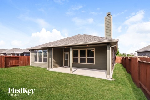 a small bungalow with a lawn and a fence