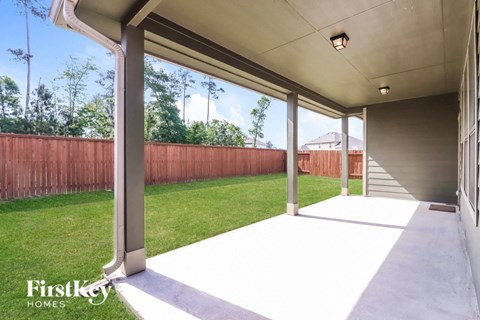 a patio in a home with a lawn and a fence