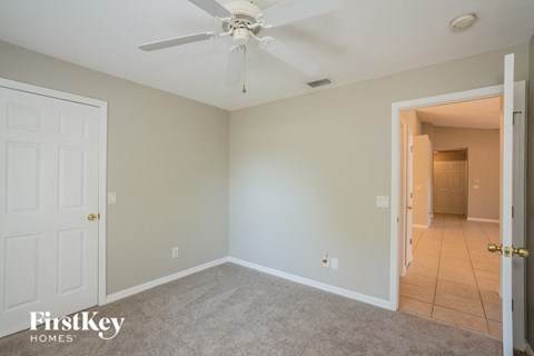 a bedroom with a ceiling fan and a door to a hallway