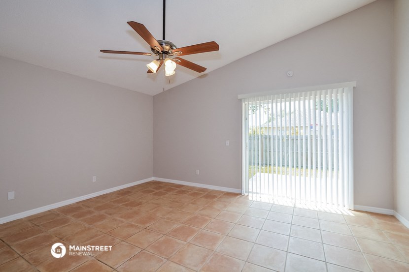 the spacious living room with ceiling fan and tile flooring