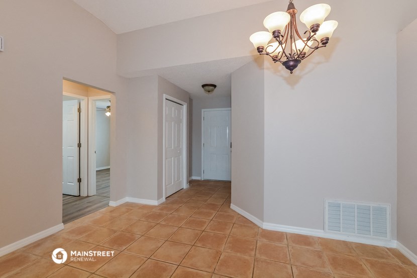a dining room with a chandelier and a door into a hallway