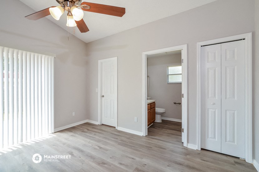 a living room with a ceiling fan and a door to a bathroom