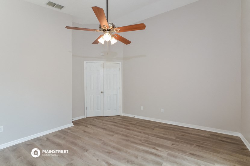 the living room of an empty house with a ceiling fan